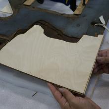 A Museum staff member places a third layer of plywood intended for use in repairing holes in a World War II era aircraft.