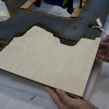 A Museum staff member places a fourth layer of plywood intended for use in repairing holes in a World War II era aircraft.