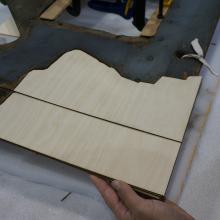 A Museum staff member places a fifth layer of plywood intended for use in repairing holes in a World War II era aircraft.