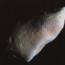 Photo showing a partial view of an oblong-shaped asteroid