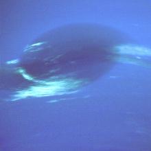 A view of Neptune's Great Dark Spot, a darker blue area of Neptune with light blue wisps near the bottom and the sides.