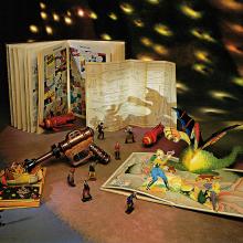 A collection of space-themed toys and comic books on a table with stars projected in the background.