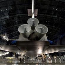 View from behind the Space Shuttle Enterprise showing three engines, tail, and lower side of wings of the orbiter.