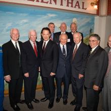 Group of men dressed in suits for an event pose for a photograph inside the Museum.