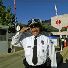 Darrell King, a security officer, smiles and performs a salute in front of the National Air and Space Museum's flagship building on the National Mall.