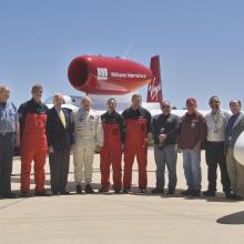 A group of eleven people stand in front of a red and white aircraft at the Udvar-Hazy Center.