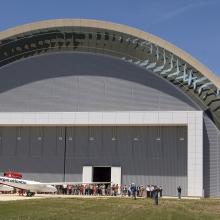 A white and red aircraft stands in front of a set of doors in the collections storage area of the Udvar-Hazy Center.