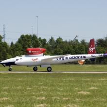 A white and red aircraft lands on a tarmac near the Udvar-Hazy Center.