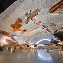 A hangar at the Steven F. Udvar-Hazy Center featuring several aircraft displayed from the ceiling or from the floor.