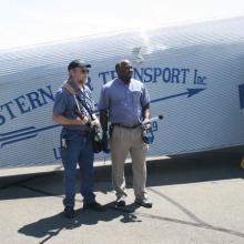 Two Smithsonian employees stand in front of white Ford Tri-Motor aircraft.