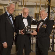 Former Museum Director Jack Dailey, pilot Robert "Bob" Hoover, and Awards Master of Ceremonies David Hartman stand together at an awards ceremony.