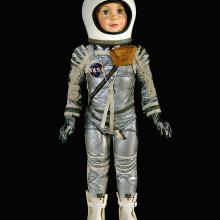 Child-size doll in silver spacesuit with white helmet and white rubber boots