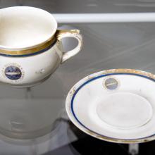 A white cup and saucer, each featuring a small depiction of the Hindenberg airship