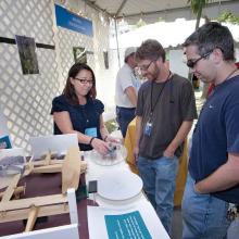 A woman displays an exhibit to patrons at the Folklife Festival.