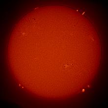 Disc view of the sun, with multiple prominences of plasma floating away from the Sun as well as sunspot clusters.