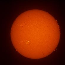 Disk view of the Sun's surface featuring a solar flare on the lower left section of disc as well as filaments and prominences throughout the disc.