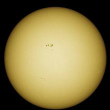 Disk view of the Sun with visible sunspot groups near the center of the Sun's visible surface.