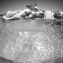 A view of the Mars Pathfinder lander, a set of paths and cushioning tarps designed to land the Sojourner rover on Mars, is passed by the Soujourner rover.