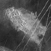 A satellite view of a set of impact craters on the surface of Venus, which looks lighter in color compared to the other sections visible.