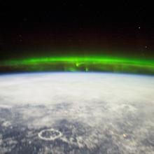 A green reflection of the Aurora Borealis seen from the International Space Station above Earth.