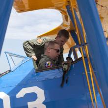 Capt. Matt Quy shows modern military curator Dik Daso how to use safety belts in the cockpit