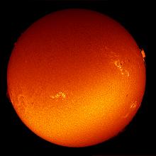 Disk view of the Sun with multiple sunspot clusters, individual sunsplots, and prominences of plasma floating above the Sun's surface.