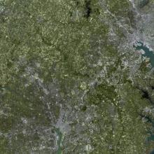 A satellite view of the Washington, D.C. and Baltimore, Maryland areas. Much green can be seen but the two cities are also visible.