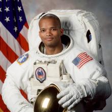 Robert L. Curbeam Jr., an African-American male astronaut, poses formally inside his astronaut suit.