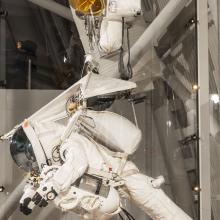 Alan Eustace's white, high altitude jumpsuit on display at the Museum. The suit is hanging in a prone position.