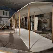 Side of wood, fabric, and metal canard biplane 1903 Wright Flyer in museum