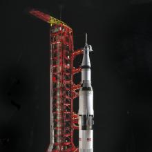 Scale model of black and white Saturn V Rocket with launch pad