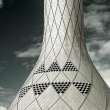 Partial view of white, conical shaped air control tower. The exterior features a tiled pattern throughout.