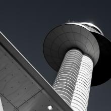 Lower view of an air traffic control tower with a double cylinder-shaped base with two circular sections combined atop the base.