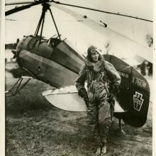 black and white photo of Amelia Earhart in front of an aircraft. 