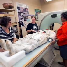 Three Smithsonian staff members prepare Neil Armstrong's spacesuit for a CT scan.