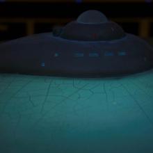 A partial view of the top portion of the Enterprise Studio Model under special lighting. Cracks can be seen on the saucer of the spacecraft from age.