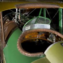 A close-up look at the interior of an airplane cockpit, which is painted green on the outside. The cockpit interior is made of polished wood, bounded by a strip of sewn leather around the rim.