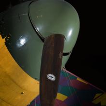 Closeup of green nose of aircraft and wooden propeller