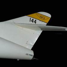 Tail of white Douglas D-558-2 aircraft with yellow stripe with "NACA" insignia and "144" written in black letters