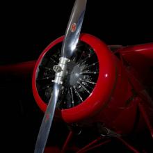 Front engine and silver single-blade propeller on red Amelia Earhart Lockheed Vega 5B aircraft