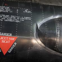 Red triangle "Danger Ejection Seat" label on side of black titanium North American x-15 aircraft