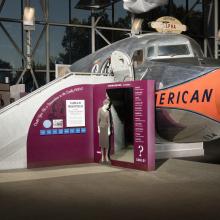 Cutoff of Douglas DC-7 aircraft in museum with exhibit panels next to stairs into aircraft