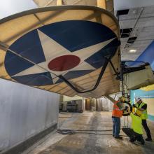 Museum staff and contractors remove the tires from the De Havilland DH-4 aircraft