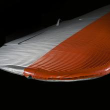 Close up view of a silver and orange painted wing of an airplane.