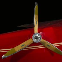 Close up image of a wood airplane propeller. The propeller is attached to a air plane. 