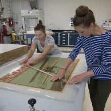 Two conservators working over an airplane print. 