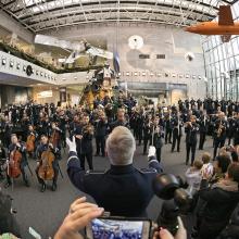 The U.S. Air Force Band performs in the museum with a large crowd of viewers in attendance.