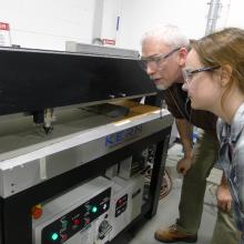 man and woman look at a larger laser cutter