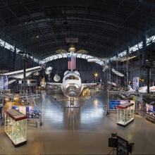 photo of the discovery space shuttle surrounded by artifacts within the Udvar-Hazy museum 