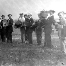 Black and white photo of photographers standing in a row. 